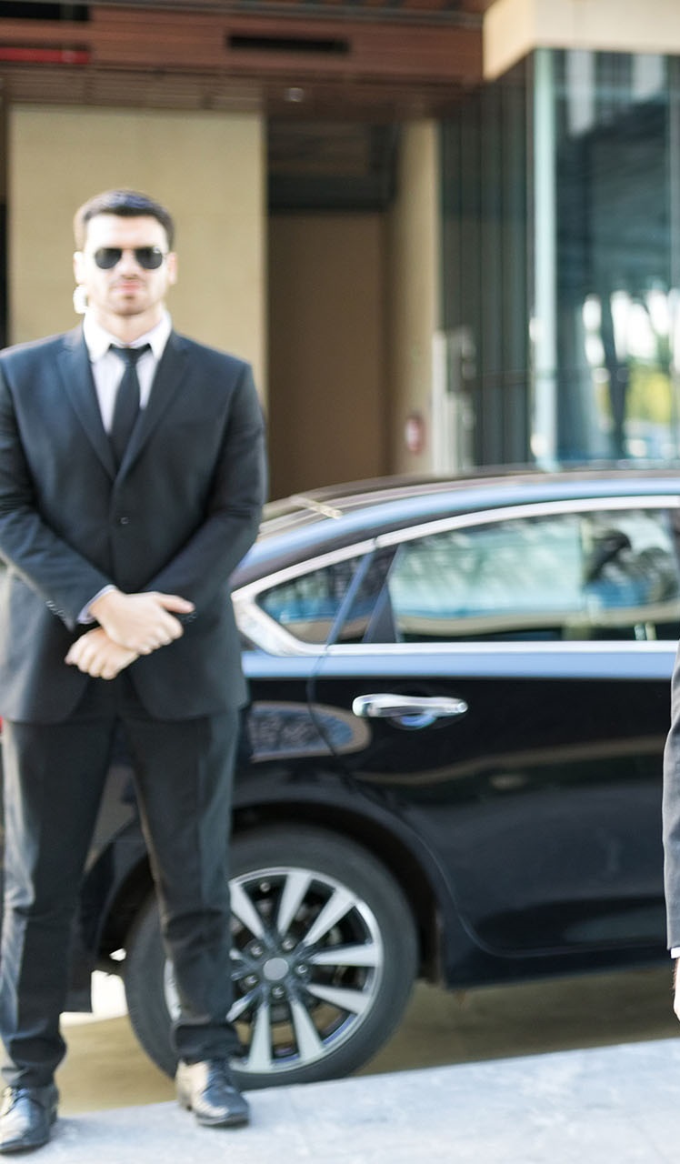 Male employer using smartphone while protection specialist walking by him